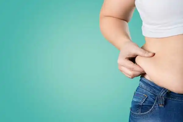 Image of woman pinching her love handles to show weight gain Henley-on-Thames